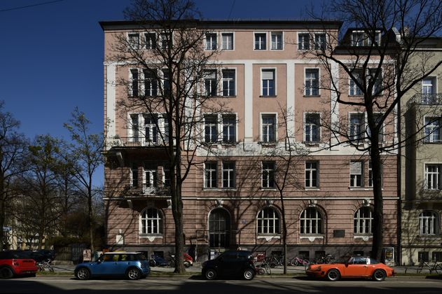 Das Eckhaus wurde in den Jahren 1896 bis 1898 zusammen mit den Häusern, Habsburgerplatz 2, 4 und dem nicht mehr bestehenden Eckgebäude Ainmillerstraße 19, nun Teil des Habsburgerplatzes, errichtet. In den Jahren des 2. Weltkriegs entstanden erhebliche Schäden, dabei wurde der Pultdachaufbau, und der flach aufgesetzte Eckturm am Dach völlig zerstört. In den Nachkriegsjahren wurde anstelle des zweiteiligen, und unterschiedlich schräg ausgeführten Dachpartie, eine weitere Etage aufgesetzt. Auch der Fassadenschmuck entlang des Habsburgerplatzes hat leider nur an vereinzelten Stellen überlebt. Der Stuck um die Fenstereinfassungen ist gänzlich verloren.[1] In keinem der verfügbaren Quellen wird ein Baumeister oder Architekt namentlich erwähnt. Seit dem Jahr 2021 ist die Fassade nun blaugrau gestrichen.