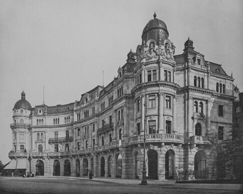 Das im italienischem Renaissancestil gehaltene Gebäude, Prinzregentenstraße 2 und 4, befand sich unmittelbar schräg gegenüber dem Prinz-Carl-Palais. Der Platz vor dem Gebäude vereinigte hier die Von-der-Tann-Straße mit der Prinzregentenstraße und auch die Königinstraße. Rechts am Haus vorbei existierte eine schräg angeordnete Verbindungsstraße zwischen der Galeriestraße und der Von-der-Tann-Straße und Prinzregentenstraße, dessen Ausläufer unmittelbar an der Harmlos-Statue begann. Das mit vielen an der Fassade und am Türmchen angebrachten Skulpturen und Freskos erbaute Haus wurde von den beiden aus Wien stammenden Architekten Viktor Siedeck (* 19. März 1856 in Napajedl, Mähren; † 26. Jänner 1937 in Wien) und Robert Tilener entworfen und erbaut durch den Baurath Brandl in den Jahren 1891 bis 1992. Im Gebäude befand sich das Cafe Prinzregent, dieses wurde am Dienstag den 18. September 1893 eröffnet. Die Decke des Hauptsaals war durch den Kunstmaler Professor Ferdinand Wagner ausgemalt, geziert mit Reliefs von Tramer. Das Gebäude war im Besitz des Ofenfabrikanten Friedrich Wamsler. Der komplette Bau wurde im 2. Weltkrieg zerstört und nicht wieder aufgebaut.