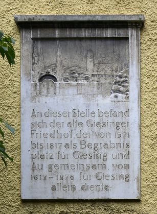 Erinnerung an den ehemaligen Friedhof. An der Fassade des Benefiziatenhauses hinter dem Spielplatz.