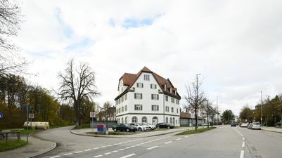 München, Perlach. Blick an der Ottobrunner Straße 128, auf eines der wenigen verbliebenen Gebäude aus den frühen 1920er Jahren entlang dieser Straße. Das Bauwerk vormals Rosenheimer Straße, Ramersdorf Hausnummer 128 einhalb, Ecke mit der ehemaligen Giesinger-Bahnhof-Straße, nun Adilostraße, trägt auch einen Höhenfestnetzbolzen mit der Nummer 2866.