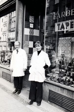 Ehemalige Drogerie, Farben-, und Tapetengeschäft von Erwin Heil. Das Foto zeigt den Drogeriebesitzer Erwin Heil mit seiner Drogistin, Erika Holusek, vor der Drogerie, Hans-Sachs-Straße 13. Foto: Schillinger 1973.