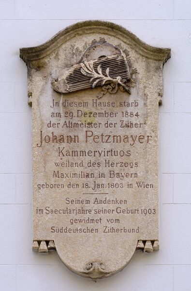 An der Fassade des Gebäudes Fürstenstraße 10. Sie mag als Erinnerung für Johann Petzmayer gelten, der hier, wir lesen den Text, In diesem Haus starb - am 29. Dezember 1884 - der Altmeister der Zither - Johann Petzmayer - Kammervirtuos - weiland des Herzogs - Maximilian in Bayern - geboren am 18. Januart 1803 in Wien - Seinem Andenken - im Saecularjahre seiner Geburt 1903 - gewidmet - Süddeutscher Zitherbund. Die Gedenktafel wurde am 9. September 1903 um 10:30 Uhr feierlich enthüllt. Im Jahr der Montage der Platte war dies die Hausnummer 19. Die aus Naturstein gefertigte Tafel wurde in den Werkstätten des Steinmetzbetriebs Lallinger angefertigt.