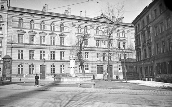 Gabelsbergerstraße an der Einmündung bei der Dachauerstraße. Zustand vor der Zerstörung im 2. Weltkrieg. im Hintergrund das ehemalige Schulhaus Gabelsbergerstraße 76. Im Vordergrund der Fischmarktbrunnen vom Viktualienmarkt.